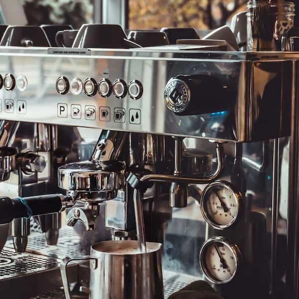 An over-head shot of someone making a latte with frothed milk from a jug