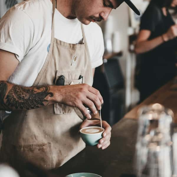 An over-head shot of someone making a latte with frothed milk from a jug