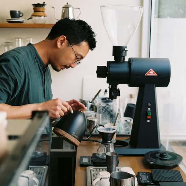 An over-head shot of someone making a latte with frothed milk from a jug